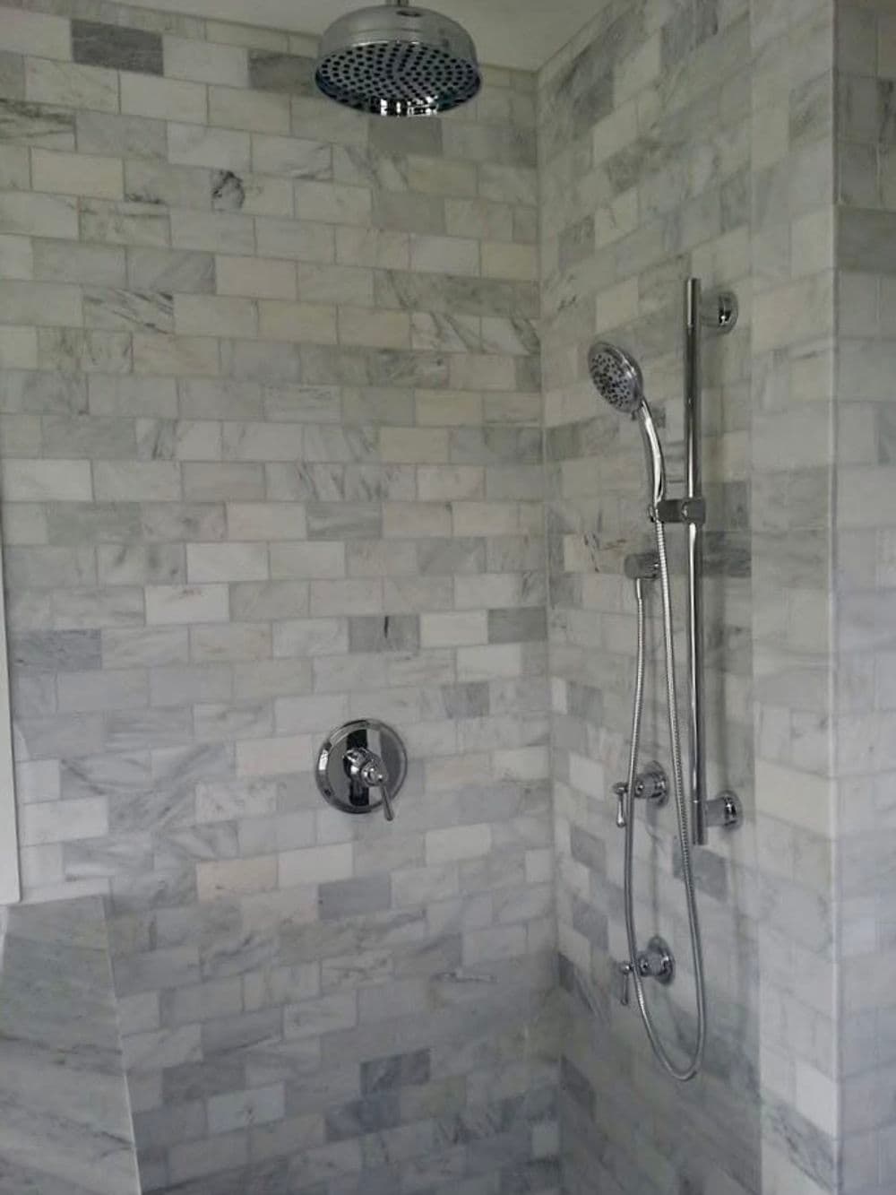 Modern shower with sleek marble tiles and high-end chrome fixtures. Elegant and stylish design.