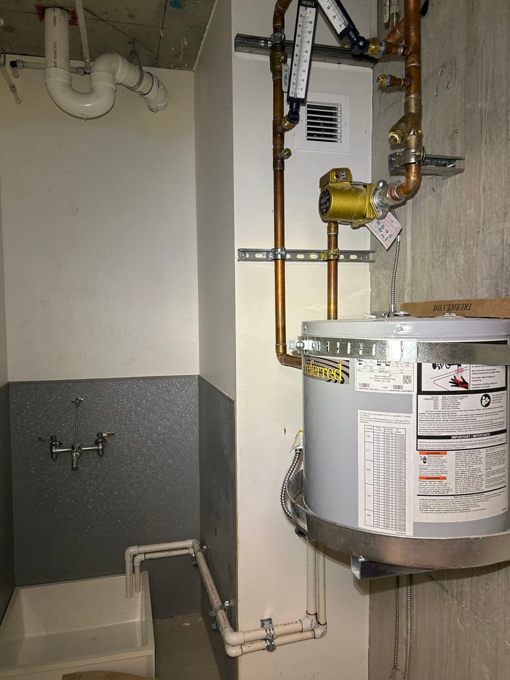 Water heater installation in utility room with plumbing and shower system visible.