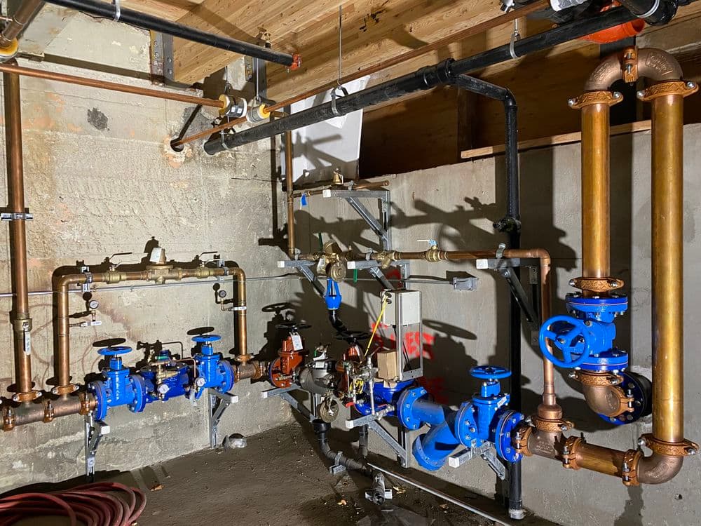 Industrial plumbing setup featuring blue valves and copper pipes in a basement setting.